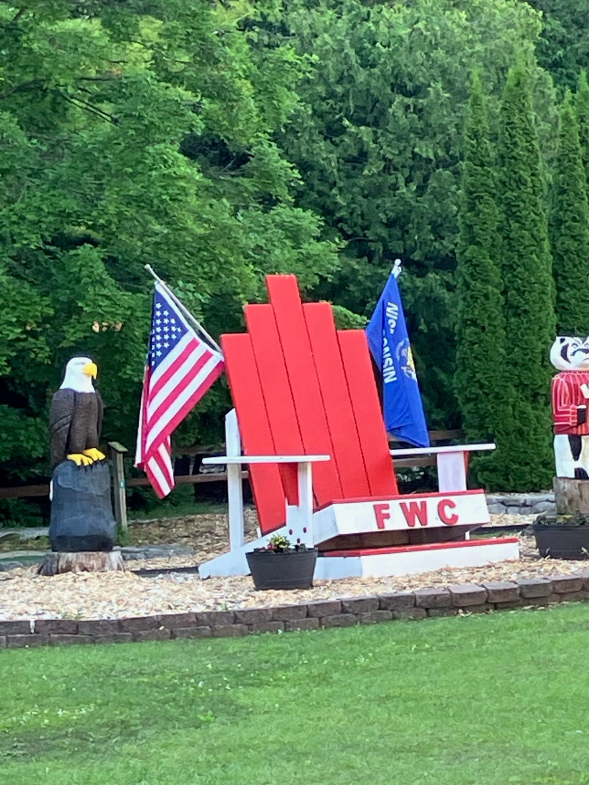 The oversized red FWC Adirondack chair and hand-carved eagle on the campground lawn